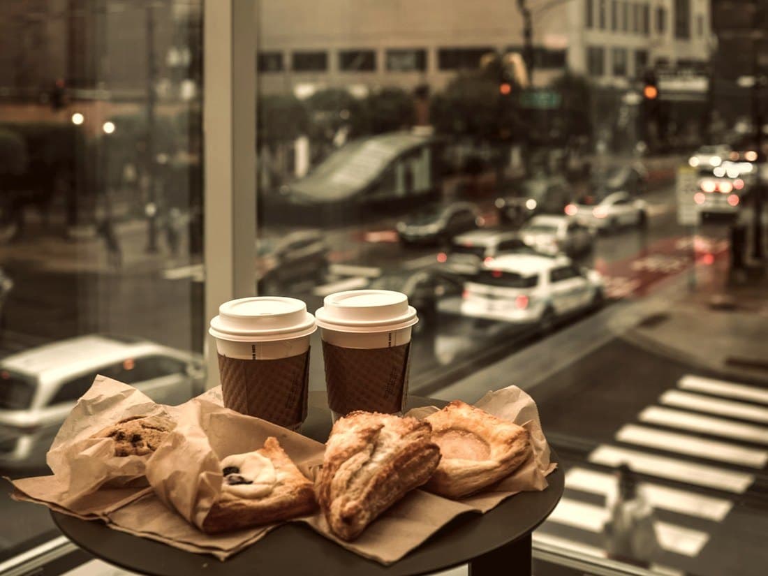 Two coffees and pastries on a table above a city street